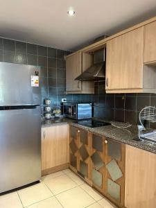 a kitchen with wooden cabinets and a stainless steel refrigerator at Two Bed rooms at Talabay Aqaba in Aqaba