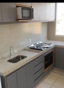 a kitchen with a sink and a microwave at Quartoo Individual in Belo Horizonte