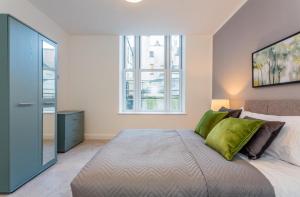a bedroom with a large bed with green pillows at Hull Central Comfort in Hull