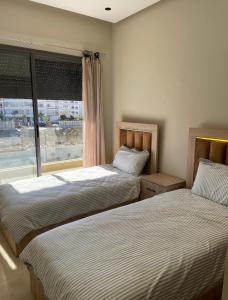 zwei Betten in einem Zimmer mit Fenster in der Unterkunft Résidence Beach Land El Mansouria in Mohammedia