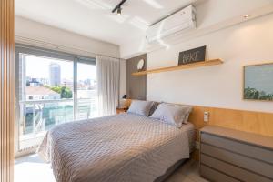 een slaapkamer met een bed en een groot raam bij Apartamento top 40m2 Trend 24 Moinhos de Vento in Porto Alegre +17 foto's