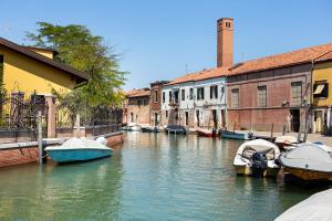un gruppo di imbarcazioni ormeggiate in un canale con edifici di WAVE'S GLASS Industrial loft in old Murano a Venezia