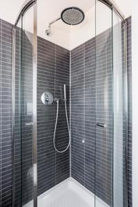 bagno con doccia e piastrelle nere di WAVE'S GLASS Industrial loft in old Murano a Venezia Altre 11 foto