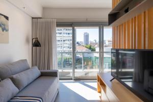 een woonkamer met een bank en een groot raam bij Apartamento top 40m2 Trend 24 Moinhos de Vento in Porto Alegre