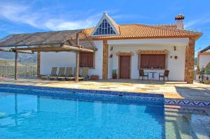 a villa with a swimming pool in front of a house at La Villa del Lago in Iznájar