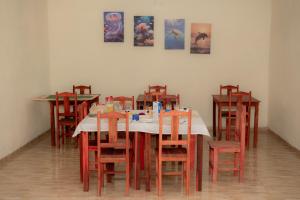 a dining room with a table with red chairs at Pousada Villa Marini in Itarema