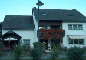 a white house with a balcony with flowers on it at Gästehaus-Weingut Michael Scholer in Schleich