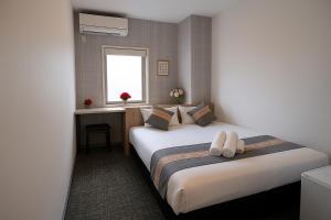 een hotelkamer met twee bedden en een raam bij Plaza In Kanku Hotel in Izumi-Sano