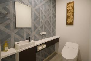 een badkamer met een wastafel, een toilet en een spiegel bij Plaza In Kanku Hotel in Izumi-Sano