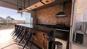 a kitchen with a bar with a bunch of stools at AP1422 ar condicionado piscina academia coworking etc in Juiz de Fora