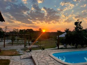 a sunset over a swimming pool with the sun setting at Chalé Rosa in Pirenópolis