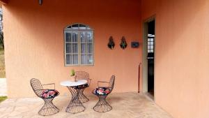 a patio with three chairs and a table and a window at Chalé Rosa in Pirenópolis