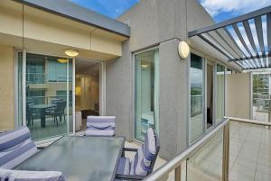 グレネルグにあるSeaside Apartment with Shared Gym & Saunaのバルコニー(ガラスのテーブルと椅子付)