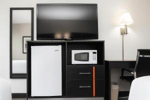a microwave and a tv on top of a black cabinet at Chaparral Motor Inn in Burlington