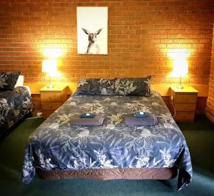 a bedroom with a bed with two lamps and a picture of a goat at 1st T Motel in Mirboo North