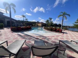 a swimming pool with two chairs and palm trees at Toy Story Getaway Retreat in Kissimmee