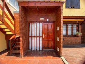 een bakstenen gebouw met een houten deur en trap bij En Esta Tierra in Villa Gesell