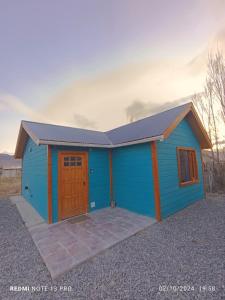 a blue shed with a door and a porch at Cabana del aeropuerto calafate in El Calafate