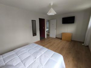 a bedroom with a white bed and a flat screen tv at Notre Dame d'Orgemont - Rose 3 in Argenteuil