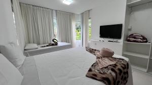 una grande stanza bianca con una televisione e un letto di Villas Pratagy- Jambu 2-Bangalô Master a Maceió