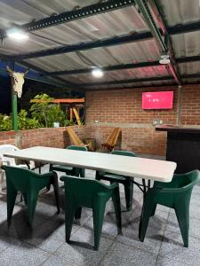 a white table and green chairs in front of a brick wall at Villa San Carlos in Juayúa