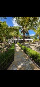 a walkway with a palm tree in front of a building at Coco Paradiso in Mechapa