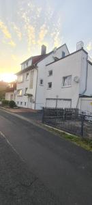 ein weißes Gebäude mit einem Zaun neben einer Straße in der Unterkunft Merci Sweet Home in Niestetal