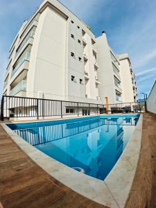 a hotel with a swimming pool in front of a building at Apê Jardins 212 - Piscina, Churrasqueira, 2 Quartos a 600m da Orla Central in Ubatuba