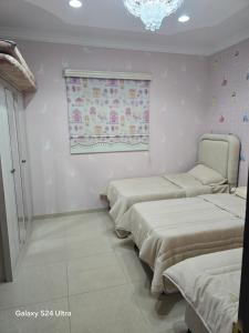 a room with three beds and a window and a chandelier at شقه مؤثثة بالشوقية in An Nikāshah