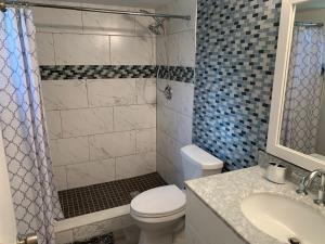 a bathroom with a toilet and a sink and a shower at Fully furnished Condo in Deerfield Beach +11 photos