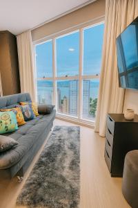 a living room with a couch and a large window at Loft vista Mar - Entre Itajaí e Balneário Camboriú in Itajaí