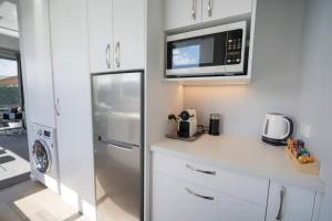a kitchen with a refrigerator and a microwave at Dusky Dream Te Anau Luxury Accommodation in Te Anau
