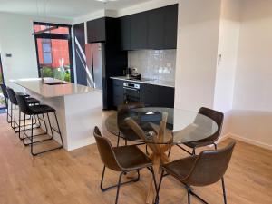 a kitchen with a glass table and some chairs at Merivale Executive Stays in Christchurch