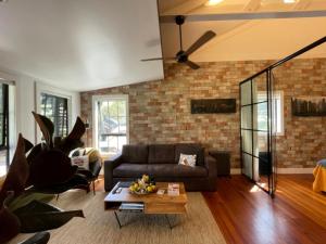 a living room with a couch and a brick wall at Moa Studios - Stay Waiheke in Blackpool