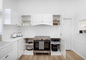 Una cocina con gabinetes blancos y una estufa. en Seabreeze Luxury Beach House Kiama, en Kiama 23 fotos más