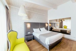 Habitación de hotel con cama y silla amarilla en Diamante MHotel en Collegno