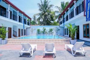 a pool in the courtyard of a building with lounge chairs at Grand Leisure Care & Wellness Resort in Negombo