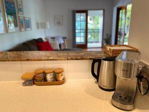 a kitchen counter with a coffee maker and jars of food at Art Deco Hidden Treasure in Brunswick Heads