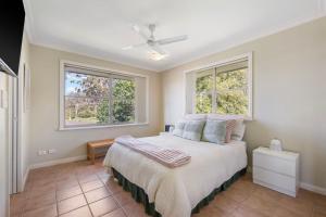 a bedroom with a bed and two windows at Slipways in Laurieton