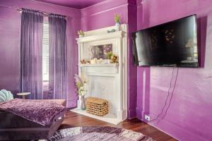 Cette chambre violette dispose d'une télévision sur un mur violet. dans l'établissement MerManor in Soda Pop District, à Wilmington