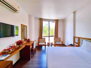 Una habitación de hotel con una cama, un escritorio y un televisor. en Khách sạn LUXURY, en Kon Rung (1)