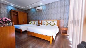 Una habitación de hotel con dos camas y flores. en Khách sạn LUXURY, en Kon Rung (1)