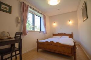 a bedroom with a bed and a desk and a window at izu花縁 in Ito