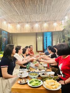 a group of people standing around a table with food at Lu's Homestay in Dong Hoi