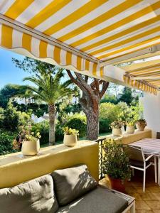 a patio with a yellow and white umbrella and plants at Casa Tropicana Family & Golf in Sitio de Calahonda