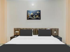 a bedroom with a large white bed and a picture on the wall at Hotel O Mellow Space in Patna +25 photos