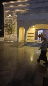 メディナにあるغرف اهل المدينه مفروشه مكيفهの夜の建物の前を歩く男