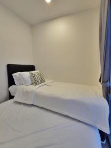 a bed with white sheets and pillows on it at LuMen By SanLiving - 3BR - NICE Expo - Free Parking in Rawalumpang