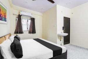 Un dormitorio con una cama blanca y un lavabo. en Hotel O Ramam, en Ayodhya