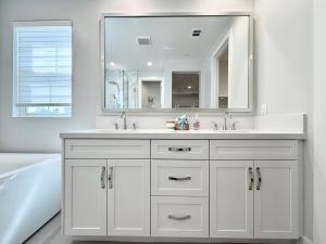 a bathroom with a sink and a tub and a mirror at #Marbella Lane - Spacious 4BR Modern Family Home! in Placentia +33 photos